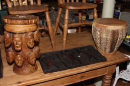 Ethnic carved wood stool decorated with carved heads,