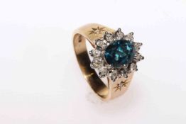 Oval blue topaz and round brilliant diamond cluster ring with a single diamond to each side on the