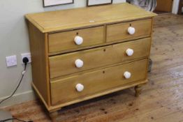 Clean pine chest of two short above two long drawers with white porcelain handles on turned feet