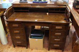 Oak roll top desk raised on four drawer pedestals with central frieze drawer