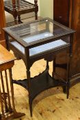 Carved ebonised bijouterie table with shaped undershelf,