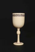 A 19TH CENTURY IVORY CUP, with knopped stem and inlaid with a band of scrolling vine.