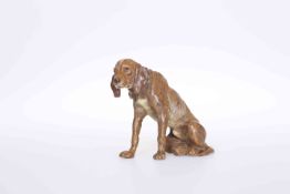 A COLD PAINTED BRONZE OF A DOG, sitting on its hind quarters.