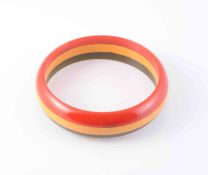 A BAKELITE BANGLE, of green, red and yellow colouring in symmetrical design. Diameter 7.5cm.