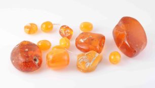 A COLLECTION OF LOOSE AMBER COLOURED BEADS, polished and rough. Approximately 130 grams.