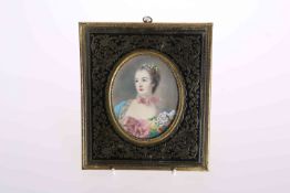 A PORTRAIT MINIATURE IN A BRASS FRAME, depicting a lady with flowers in her hair,