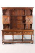 AN OAK DRESSER AND RACK, the enclosed rack with a pair of cupboard with carved fronts,