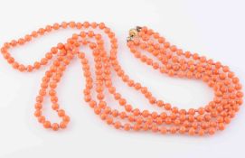 A CORAL BEAD NECKLACE, of uniform polished coral beads each strung knotted into two graduating rows,