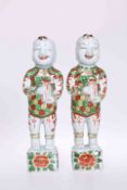A PAIR OF CHINESE FIGURES OF HAPPY BOYS, painted in the famille verte palette,