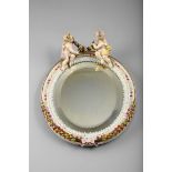 Continental Porcelain Framed oval shaped wall mirror with two applied Cherubs with a garland of