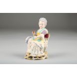 Continental Porcelain Figure, lady sitting in a chair sewing, raised on a pierced Rococo base,