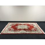 A fringed embossed Chinese carpet on red ground,