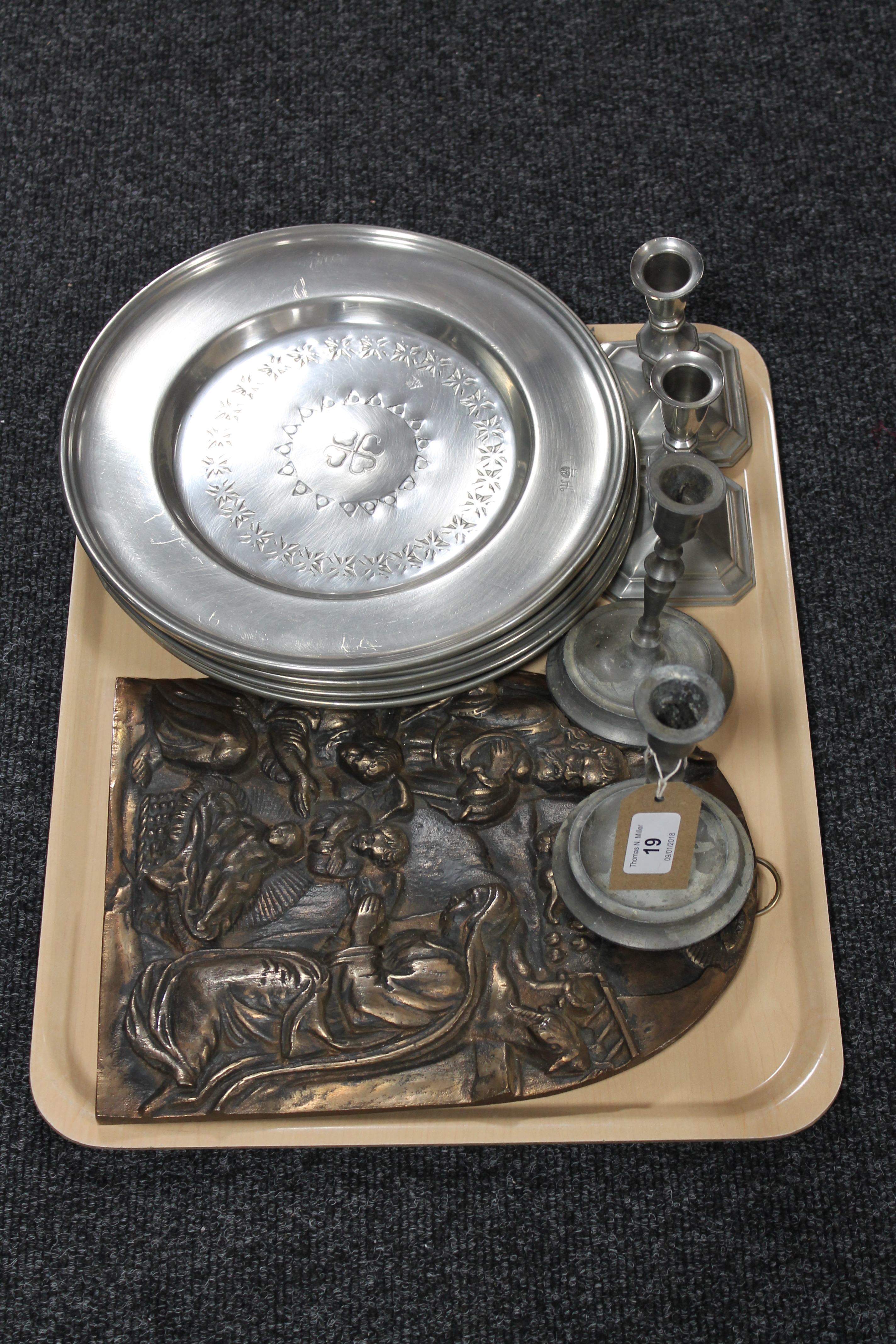 A tray of six circular pewter chargers, a cast metal plaque depicting a nativity scene,