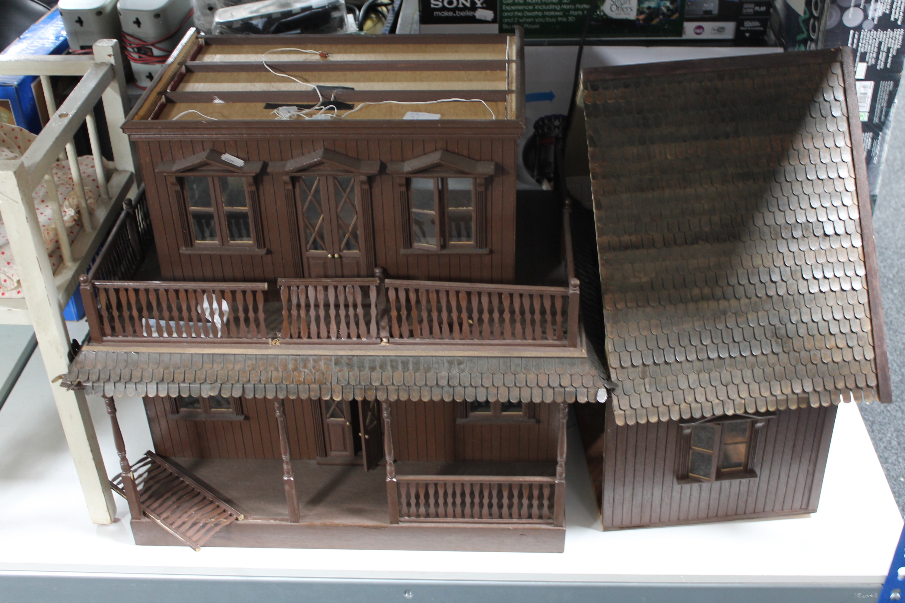 A three tier wooden doll's house together with a doll's cot containing clothing