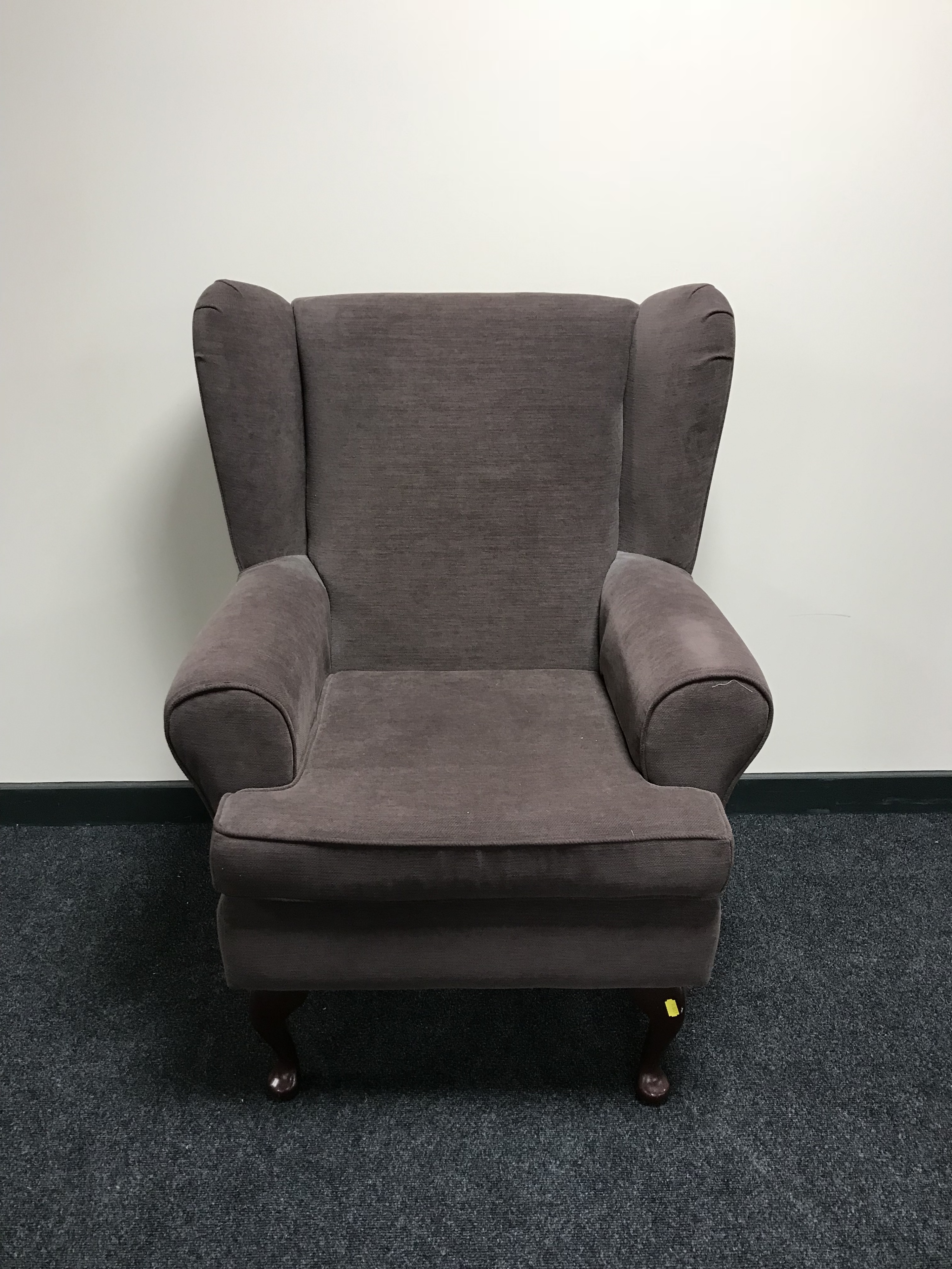 A wing back armchair in a brown fabric