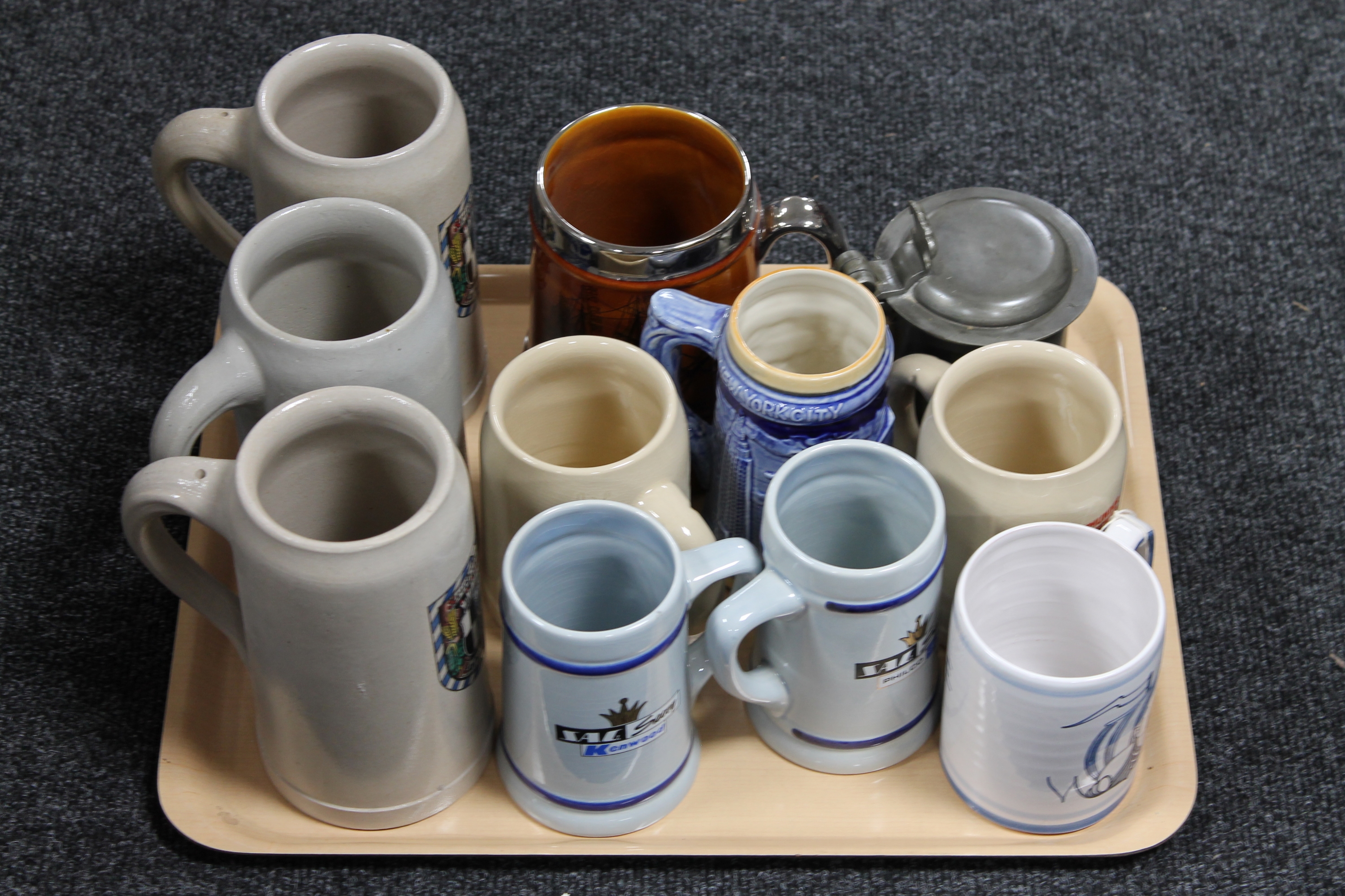 A tray of ten pottery steins together with a pewter lidded stein