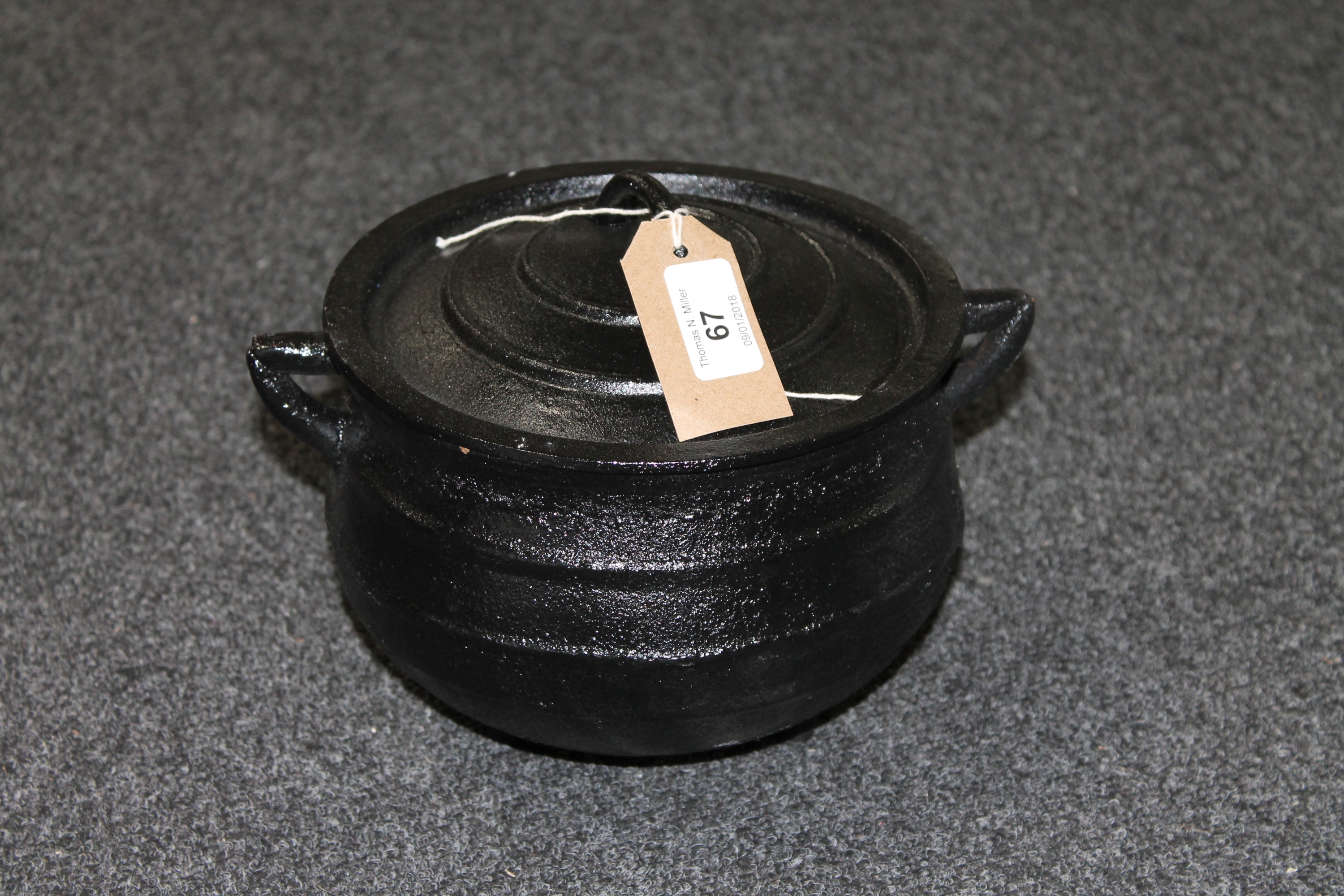 A cast iron three leg pot with lid