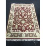 A fringed woollen Persian design rug on a red ground