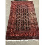 A fringed Persian rug on red ground