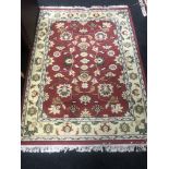 A fringed woollen Persian design rug on a red ground