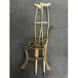 A pair of vintage wooden crutches together with a set of cast iron bench ends