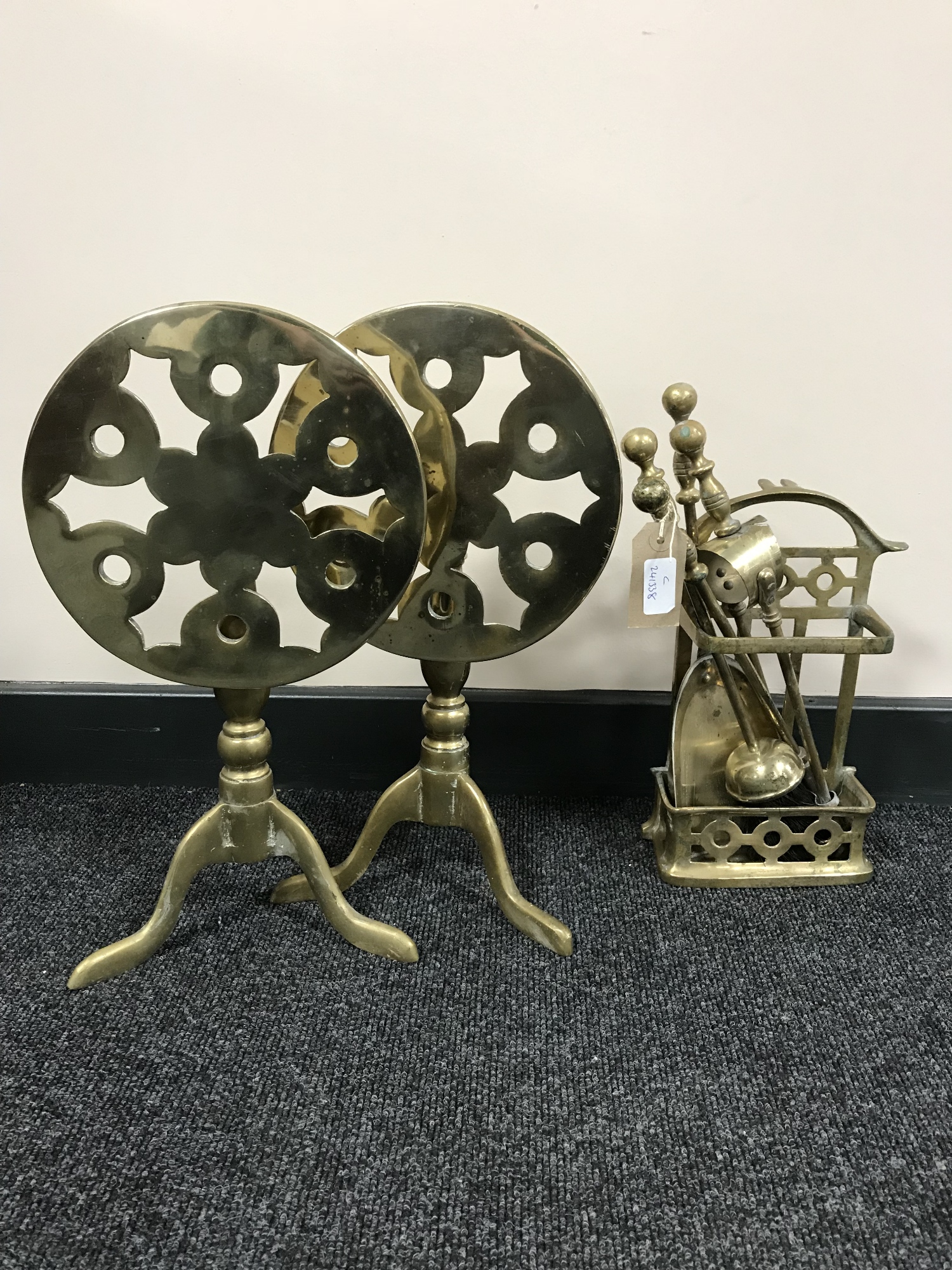 Two folding brass trivets together with a brass companion set on stand