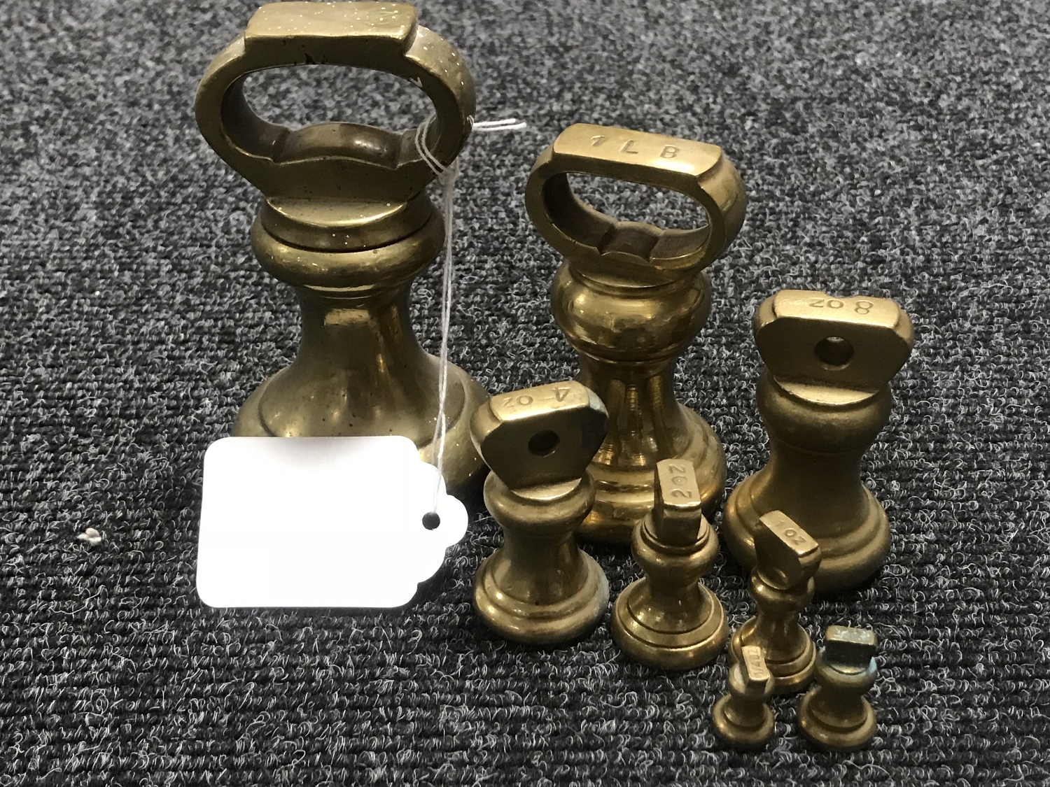 A graduated set of eight brass weights ranging from 2lbs to 1/4 oz