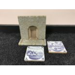 A tray of two Delft blue and white tiles and a miniature fireplace