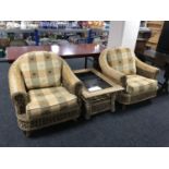 A pair of wicker conservatory armchairs and glass top coffee table