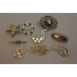 A collection of silver brooches