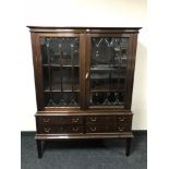 A mid twentieth century mahogany double door display cabinet fitted with four drawers beneath