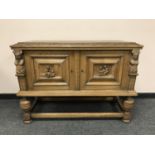 A carved oak low cabinet with double doors,
