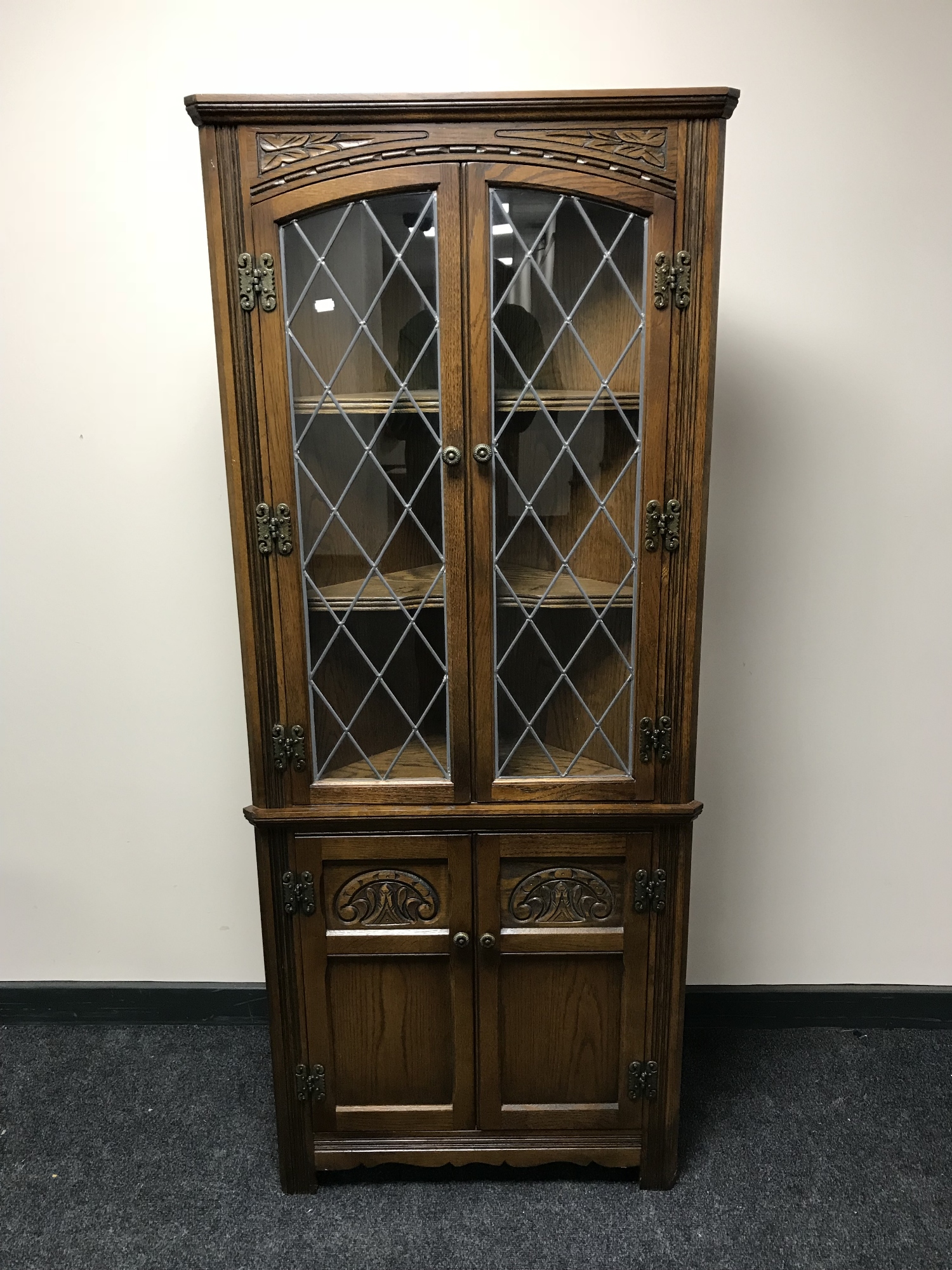 A carved oak double door corner cabinet