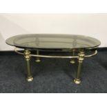 A mid 20th century oval brass coffee table with smoked glass top, 61 cm x 111 cm.