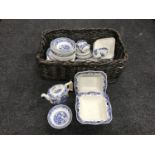 A wicker log basket containing Masons blue and white dinner ware