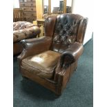 A brown button leather wing chair