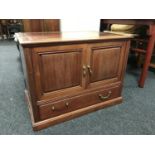 A contemporary hardwood double door low cabinet fitted a drawer