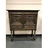 An early 20th century carved oak double door cabinet on barley twist stand, width 116 cm.