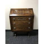 A carved oak bureau with metal handles