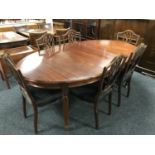 A circular mahogany dining table on reeded legs with three leaves and six shield back dining chairs