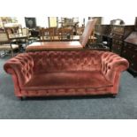 A late Victorian button backed Chesterfield settee raised on ceramic castors