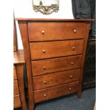 A contemporary stained pine five drawer chest