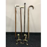 A pair of brass fire dogs together with a white metal mounted walking stick with bone handle,