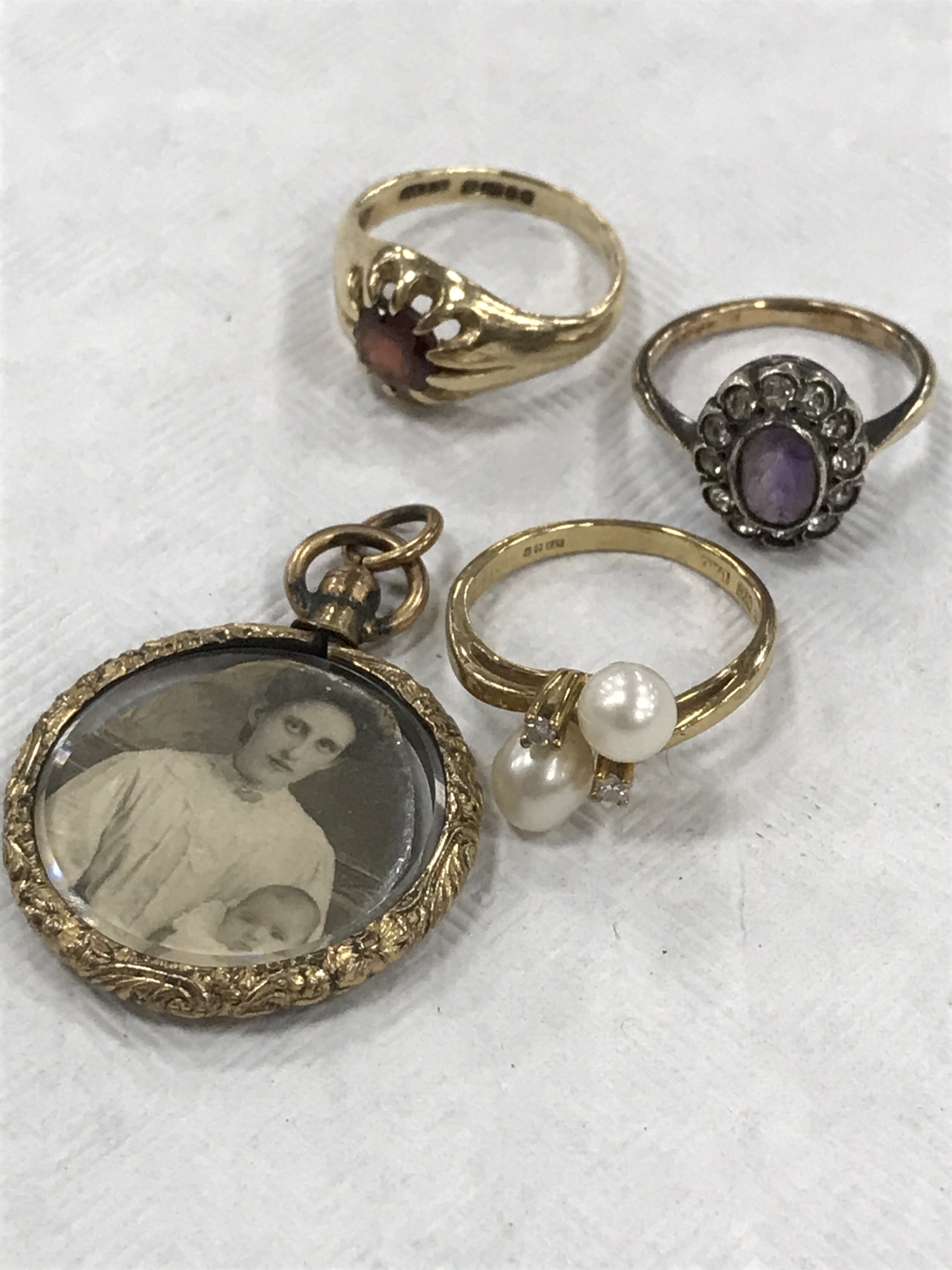 A 9ct gold garnet set ring, together with two 9ct gold dress rings and an antique locket.