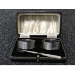 A pair of cased silver napkin rings together with a silver pickle fork