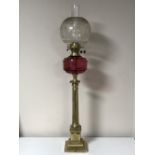 An antique brass Corinthian column oil lamp with chimney and shade