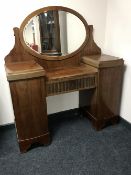 An early 20th century knee hole dressing table with pillar cabinet supports and an oval mirror