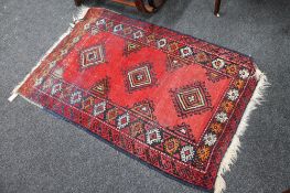 A fringed woollen Persian rug on red ground