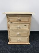 An unfinished pine four drawer bedside chest