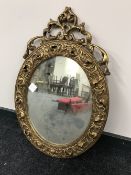 An antique ornate gilt framed oval mirror